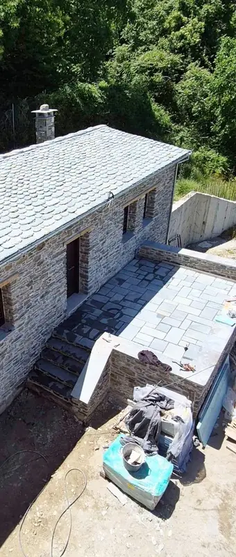 Haus mit Schieferdach, Terrassenpflaster und Treppe im Bau